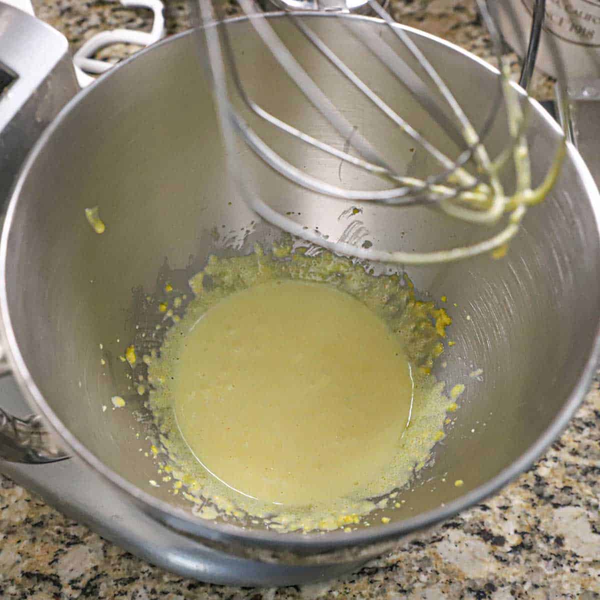 A view into the bottom of the bowl of a stand mixer that has eggs yolks that have been vigorously whisked with sugar, cornstarch, and salt.