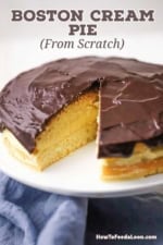 A classic Boston cream pie resting on a cake stand with a slice missing.