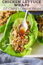 A person using a small spoon to drizzle a spicy red sauce over the top of a copycat P.F. Chang Chicken Lettuce Wrap.