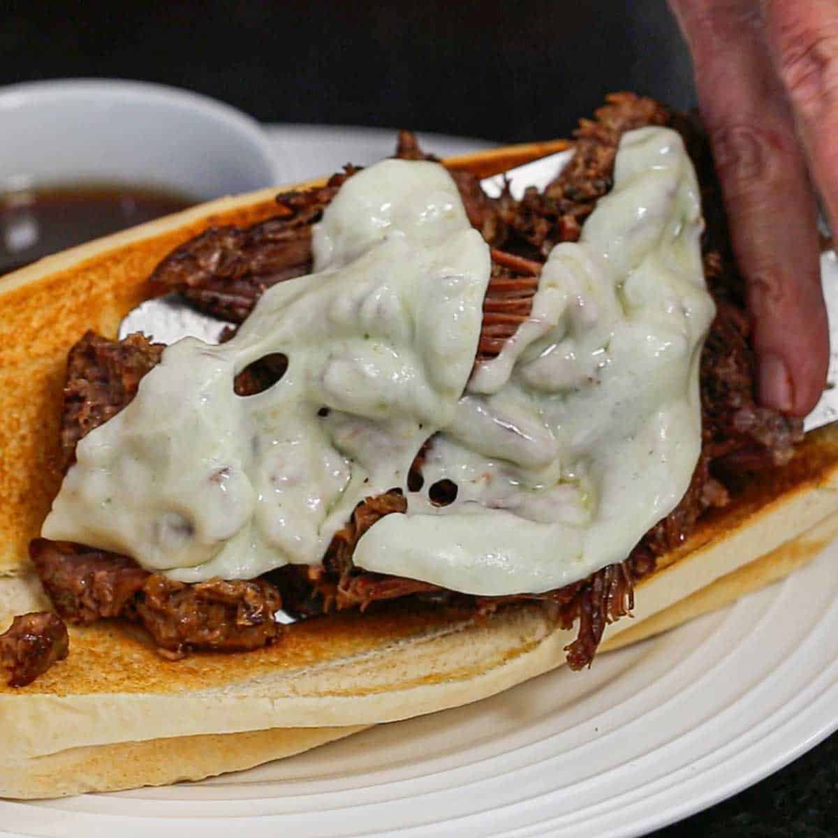 A person using two hand to lift a slow cooker French onion dip