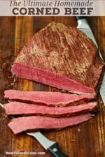 An overhead view of a homemade corned beef sitting on a wooden cutting board with several slices cut and showing the bright red hue of the meat.