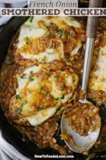 An overhead view of a skillet filled with three servings of French onion smother chicken with a large serving spoon resting in between the chicken cutlets.