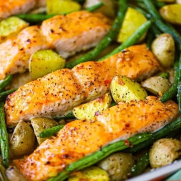 A close-up view of sheet pan honey garlic salmon and roasted veggies next to a colorful linen.