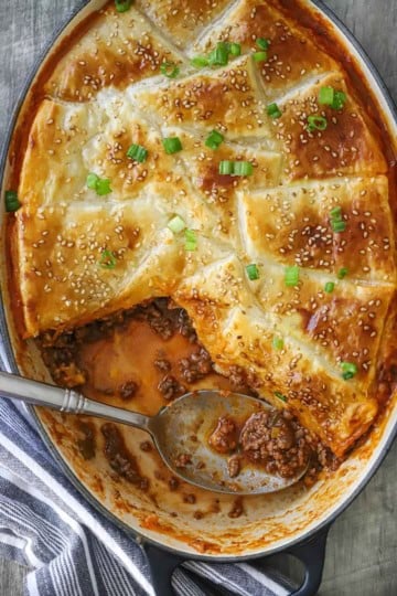 An overhead view of a Sloppy Joe Casserole in an oval baking dish with a portion of the casserole missing.