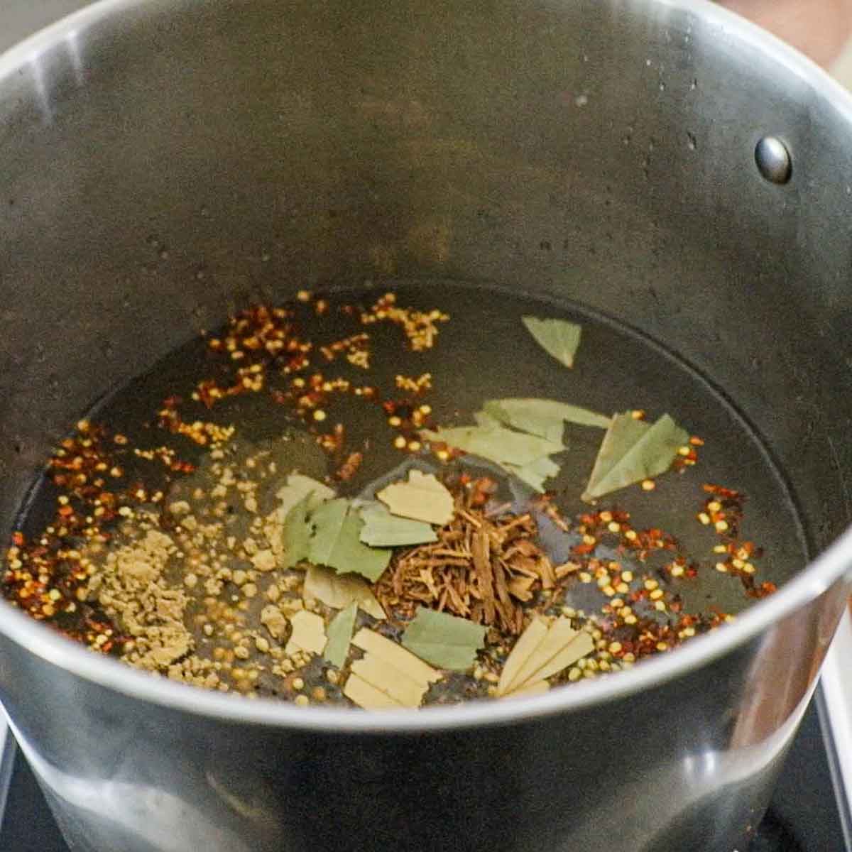 A large pot filled water, kosher salt, brown sugar, Prague Powder #1, and pickling spices including chopped up bay leaves and crushed cinnamon sticks.