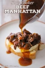 A person pouring brown gravy from a glass gravy boat over the top of a serving of slow cooker beef Manhattan on a white dinner plate.