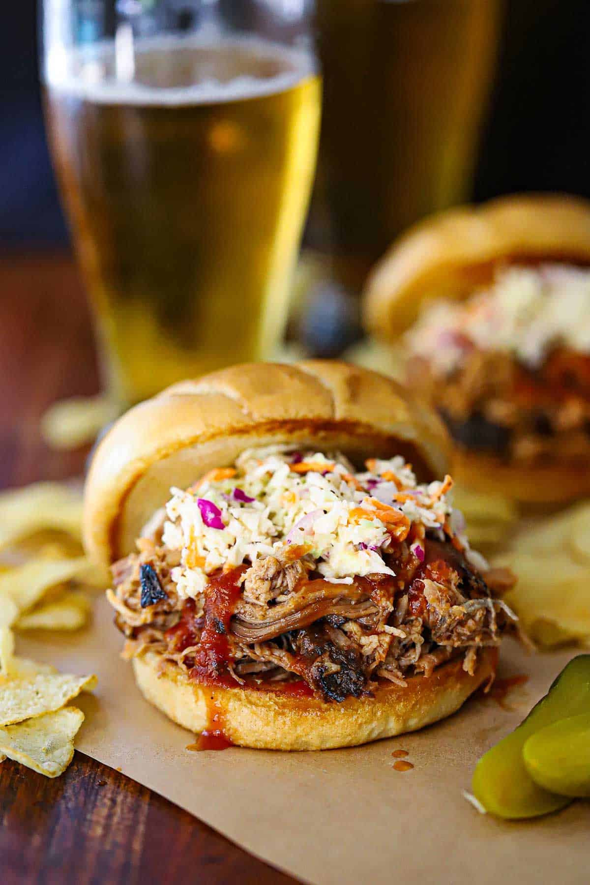 A straight-on view of a smoked pulled pork sandwich that is topped with Carolina BBQ sauce and homemade coleslaw.