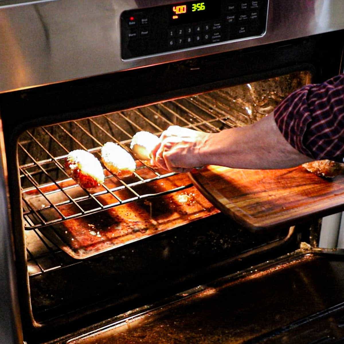 A person placing salted russet potatoes on an oven grate in an oven set to 400°F.