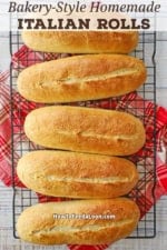 A row of freshly baked homemade Italian rolls cooling on a baking rack.