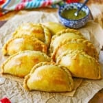 A close-up view of two rows of Argentine Beef Empanadas on a sheet of crinkled brown paper.