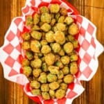 An overhead view of a basket lined with red and white-checkered paper and filled with Classic Southern Fried Okra.